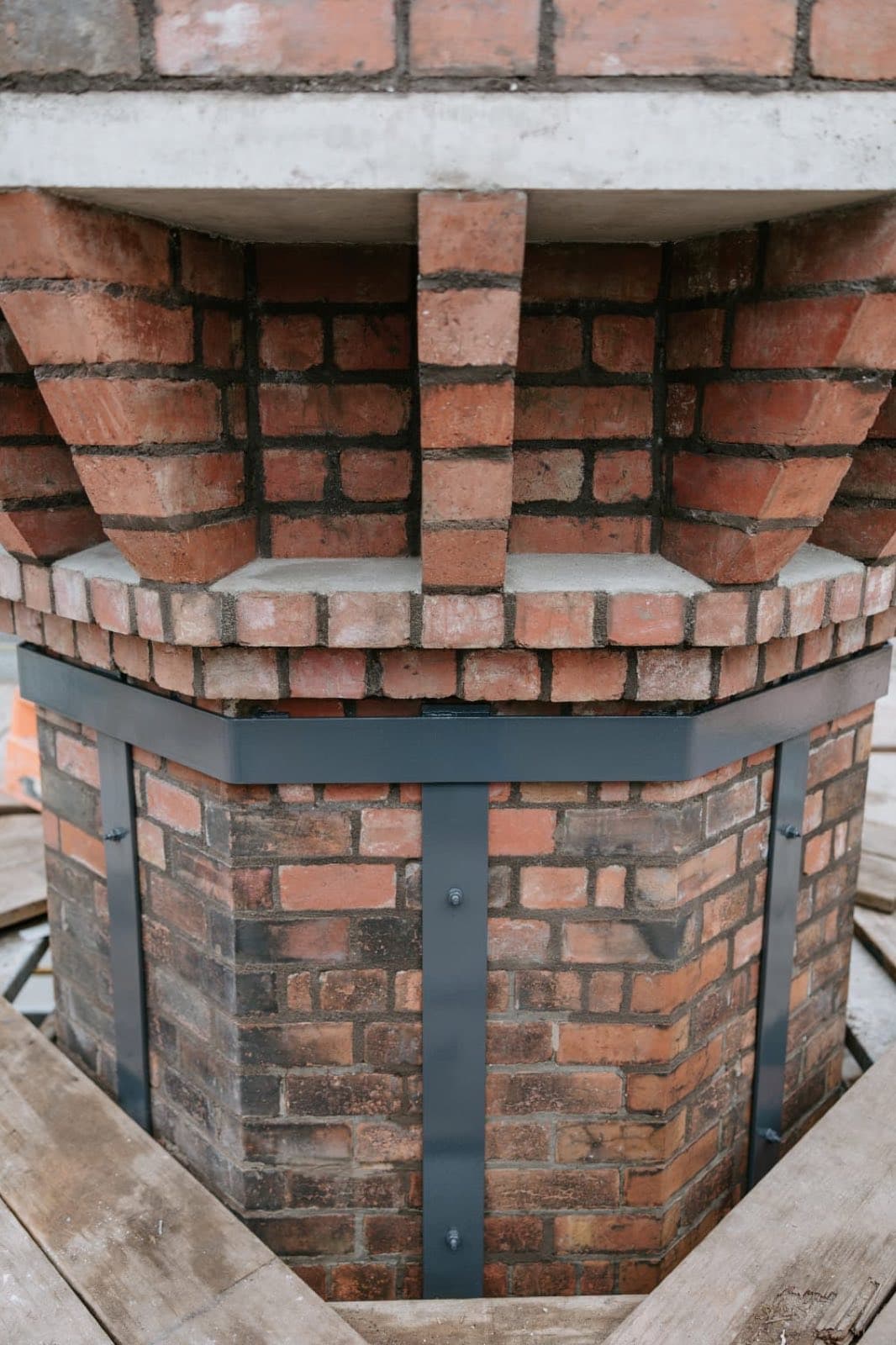 The rebuilt corbelled crown of the Old Licorice Factory chimney seen from below, with steel banding around the stack, Brunswick