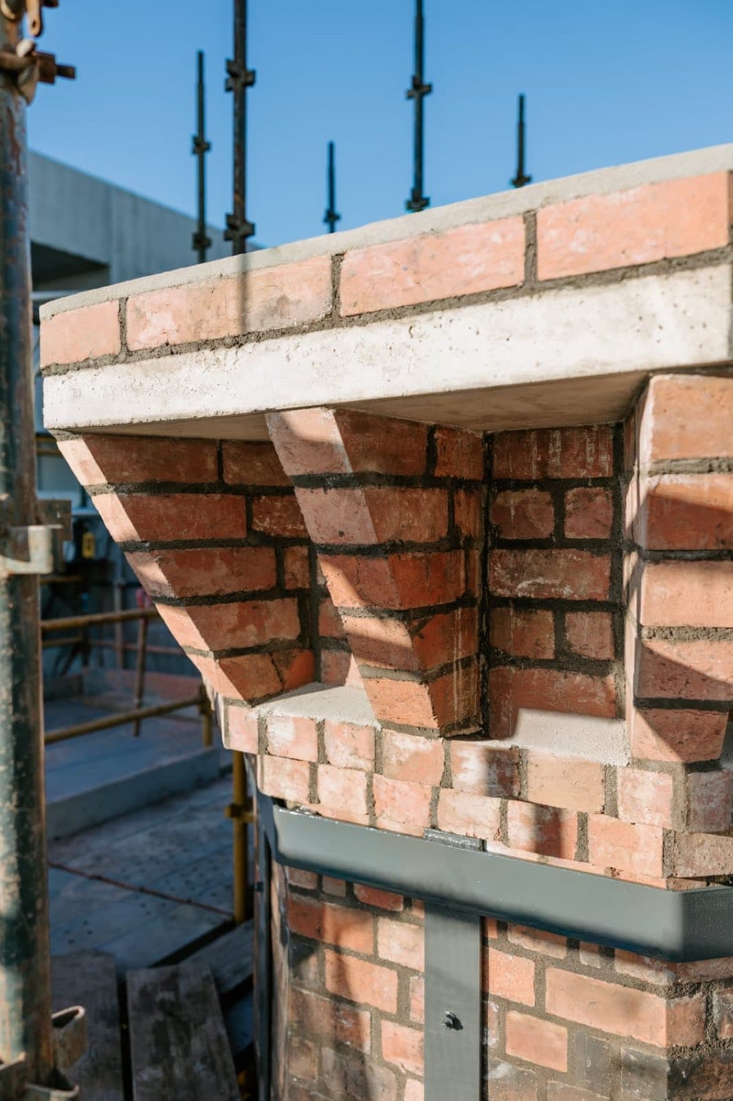Corbelled brickwork stepping out beneath the capping of the restored Old Licorice Factory chimney, Brunswick