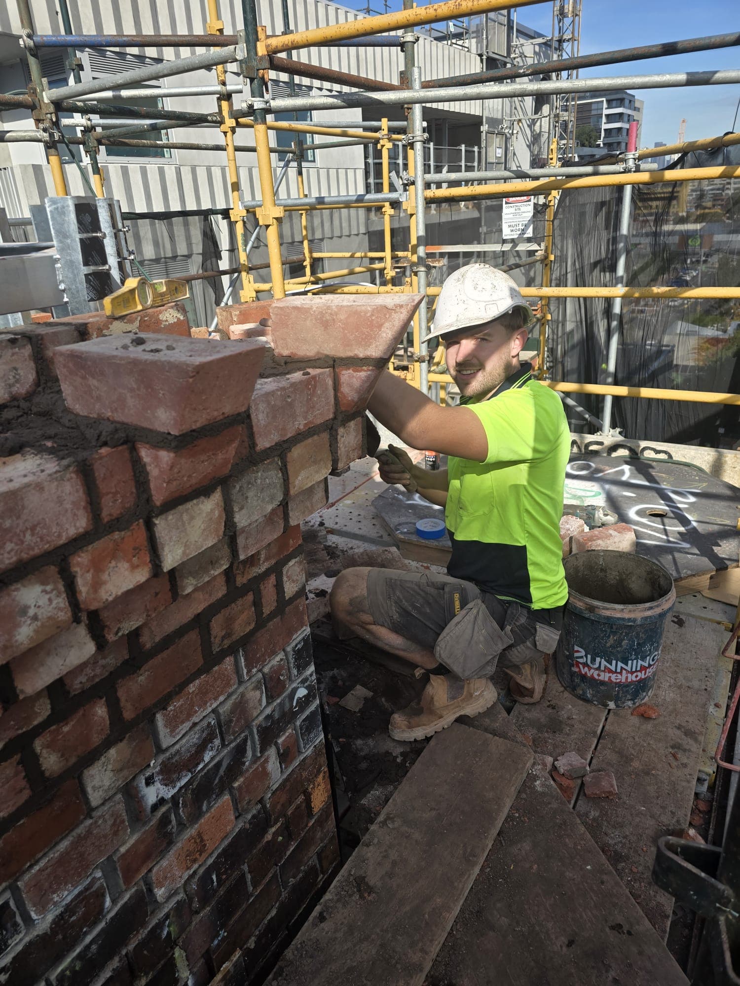 Goodwin Bricklaying craftsman rebuilding the Old Licorice Factory chimney crown at height in Brunswick