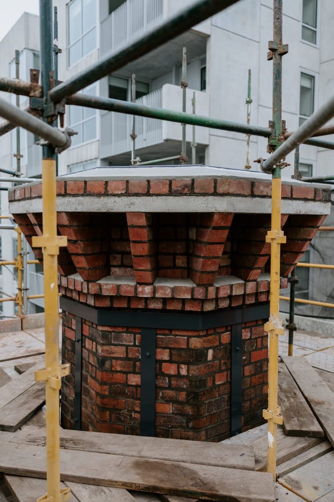 The rebuilt Old Licorice Factory chimney crown framed by scaffolding above the Brunswick development