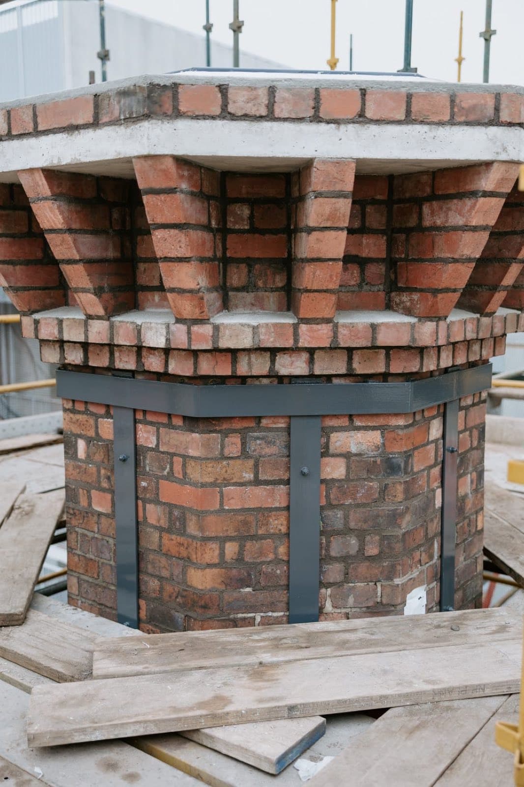 The octagonal chimney crown of the Old Licorice Factory under rebuild on a timber scaffold deck in Brunswick