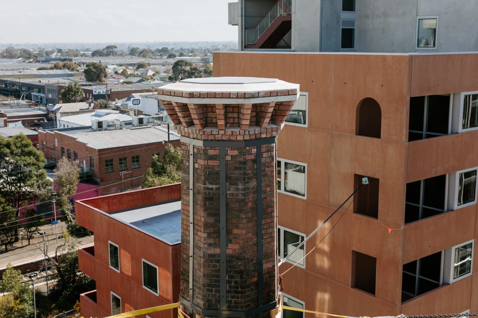 The restored octagonal brick chimney of the Old Licorice Factory standing over the Brunswick rooftops, rebuilt by Goodwin Bricklaying