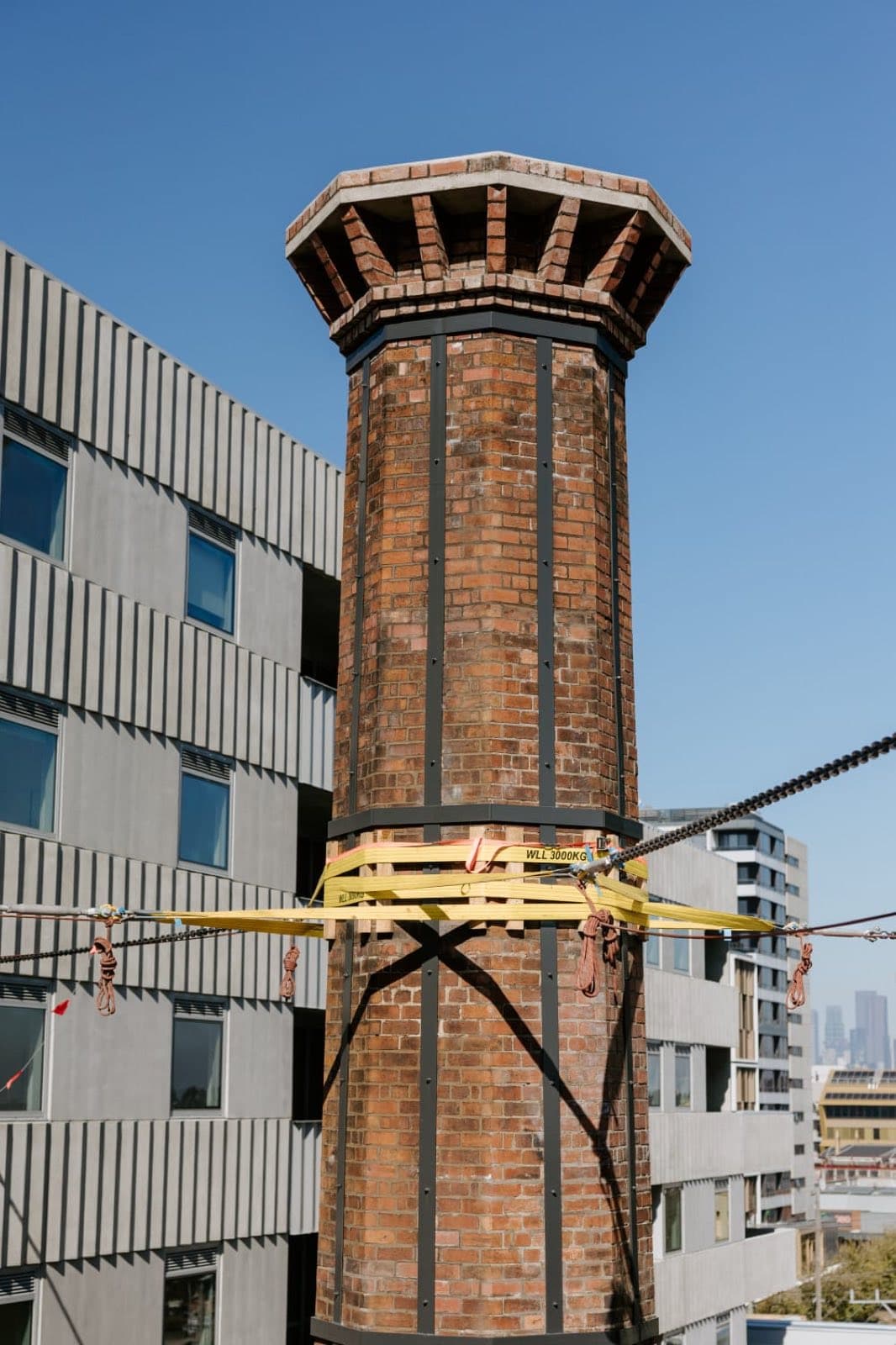 The restored Old Licorice Factory chimney lit by afternoon sun above the surrounding Brunswick development