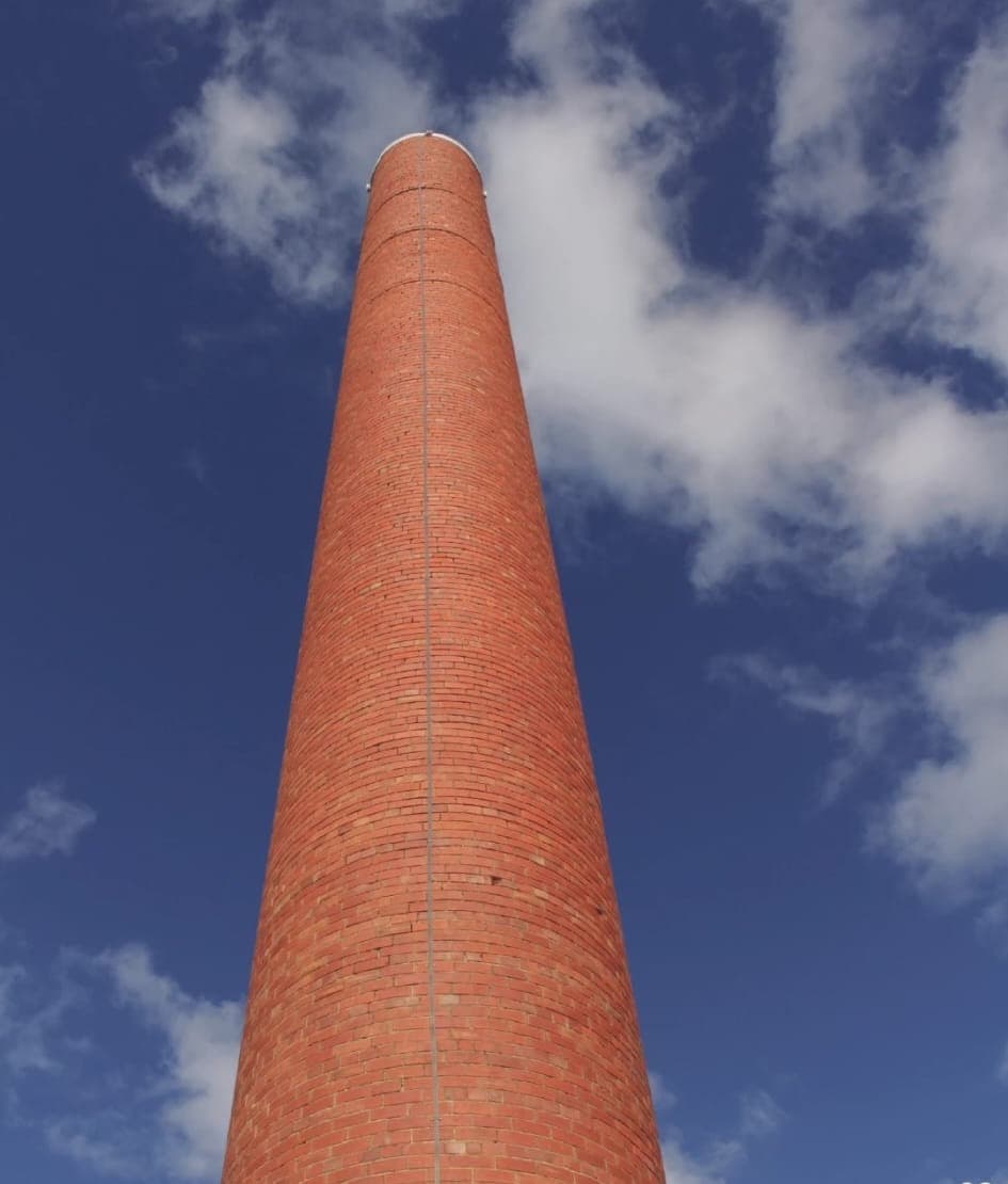 The restored 27-metre Highett Gasworks heritage chimney standing against a blue sky, by Goodwin Bricklaying