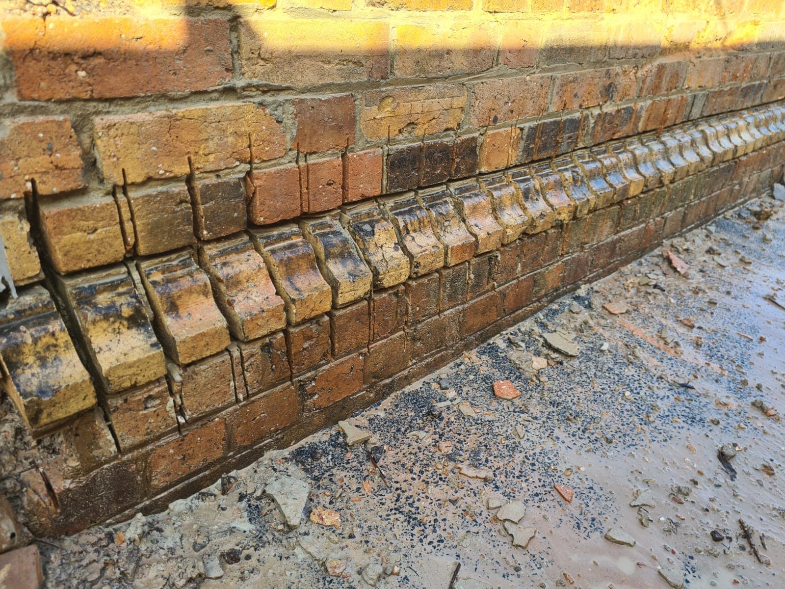 The base of the original Cairo flats wall during careful deconstruction, with the corbelled course lifted and reinforcement exposed