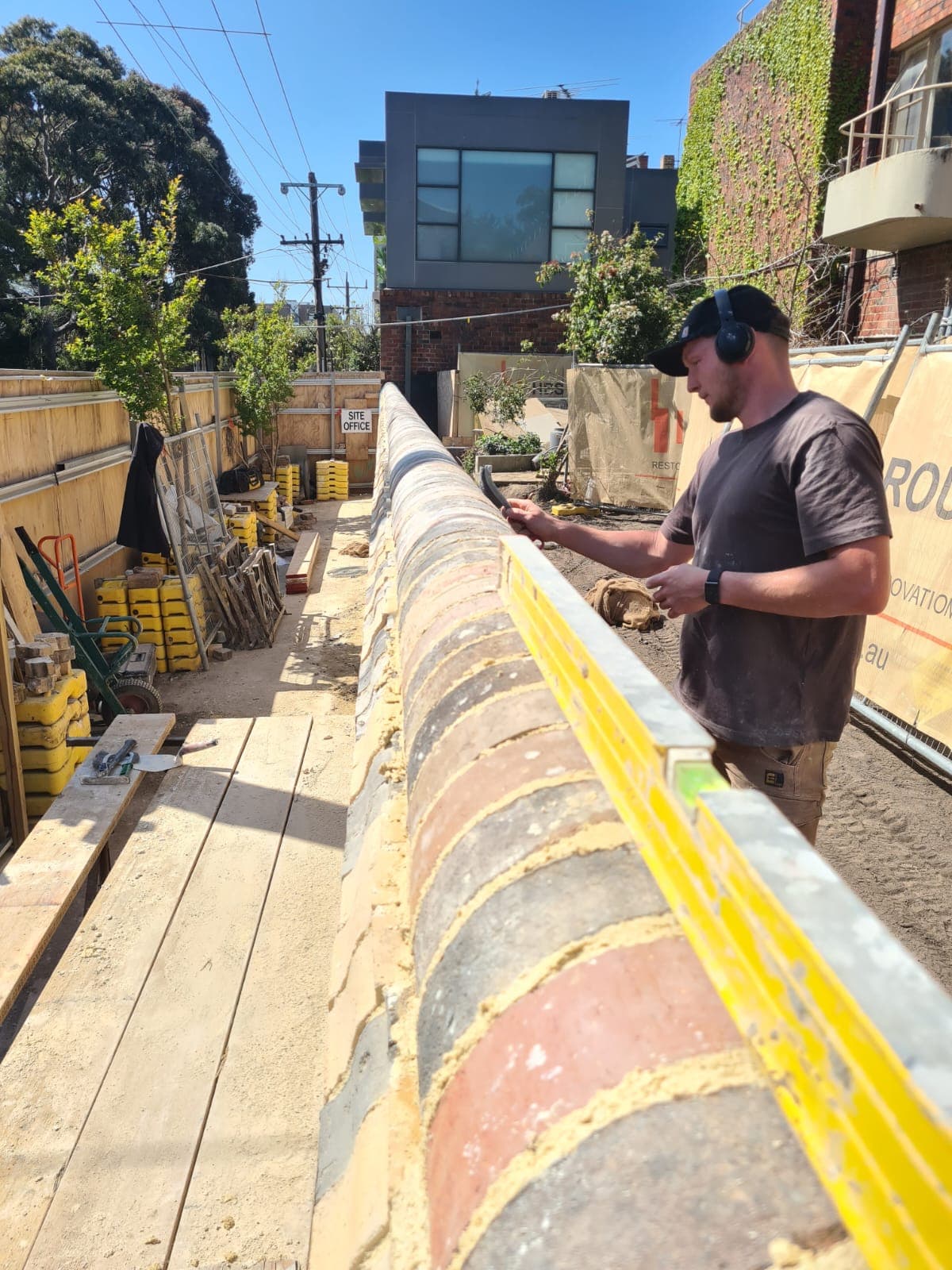 A bricklayer checking the level along the rounded brick capping course of the rebuilt Cairo flats wall