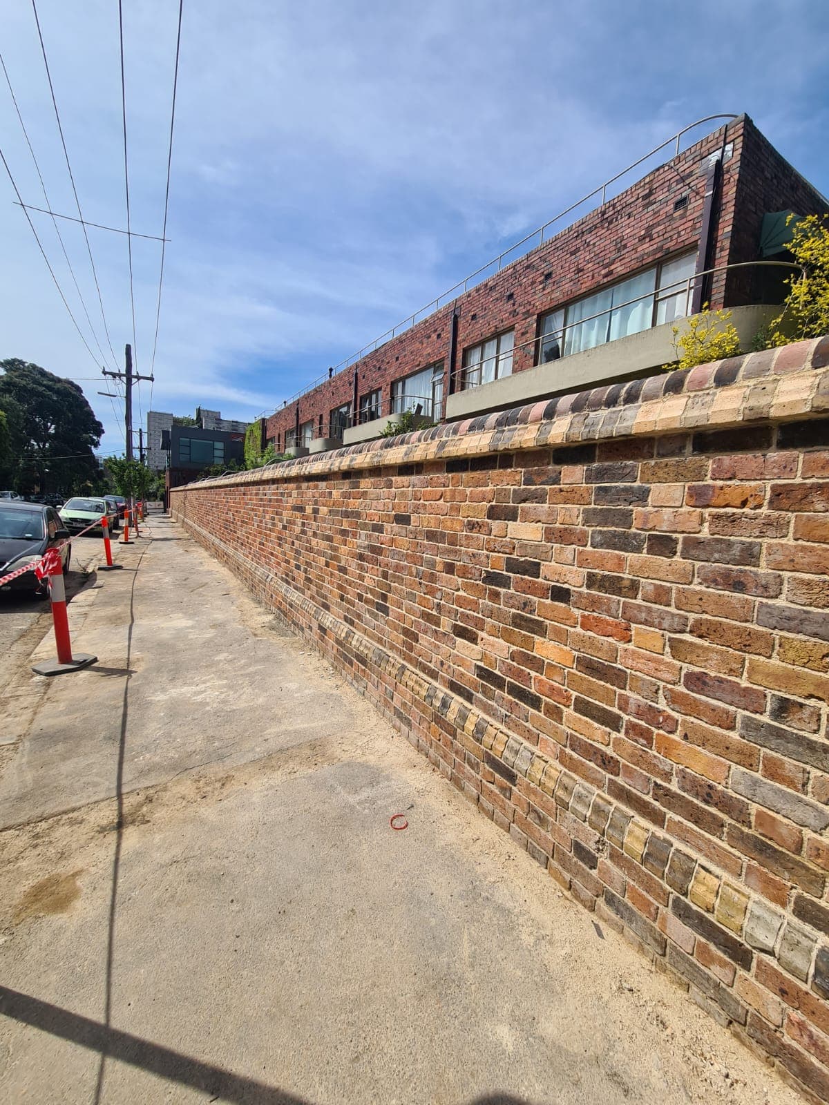 The completed heritage boundary wall running the length of Hanover Street, Fitzroy, with the Cairo flats rising behind it, rebuilt by Goodwin Bricklaying