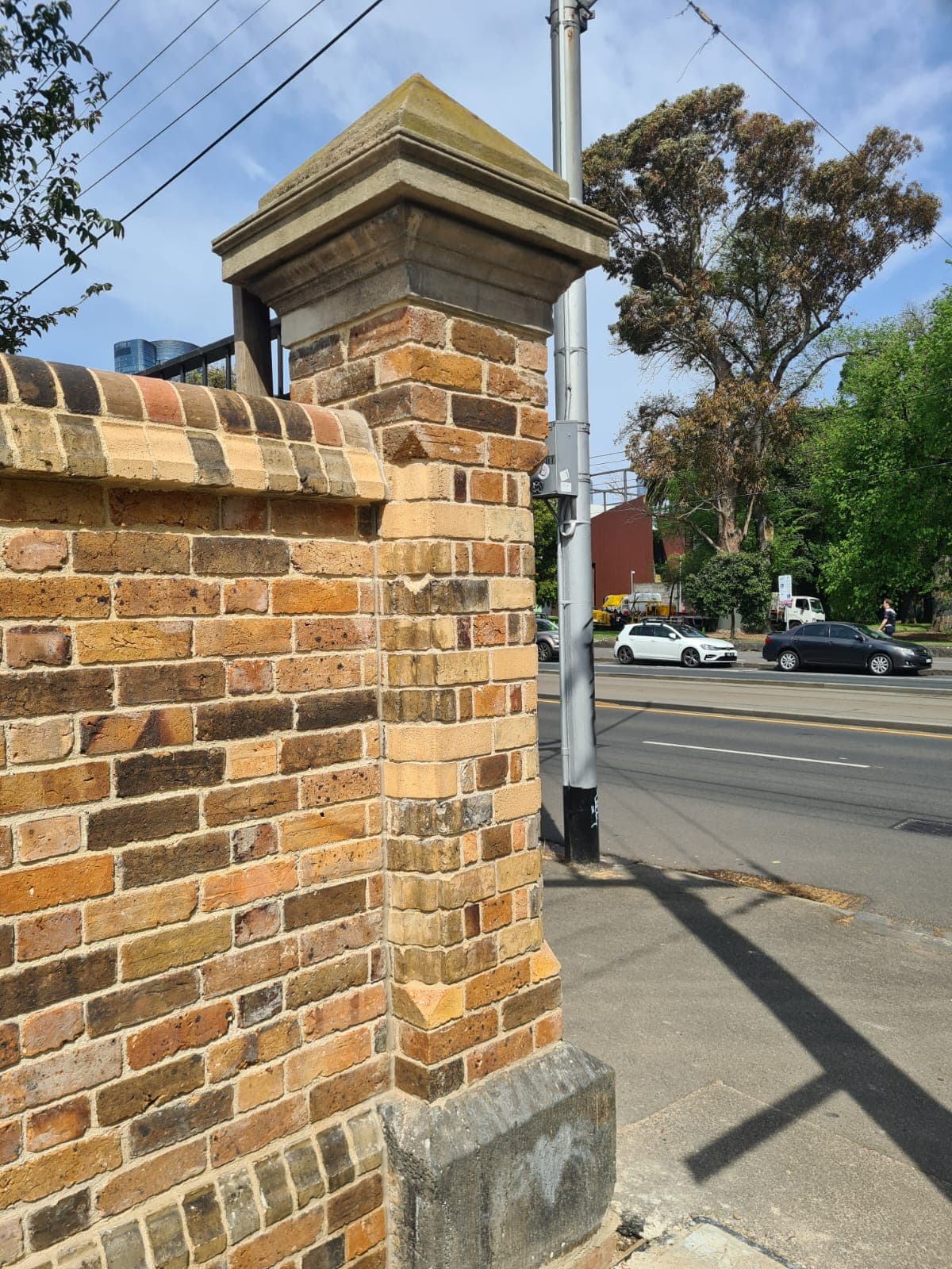 A rebuilt brick pier crowned with its original sandstone cap on the frontage of the Cairo flats wall, Fitzroy