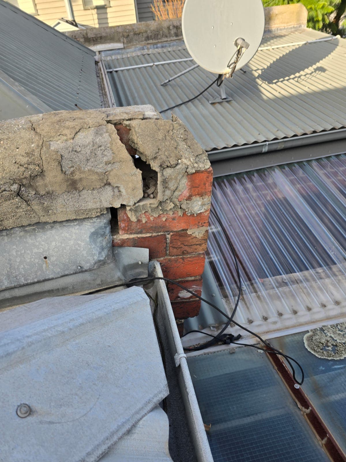 Cracked and spalling heritage chimney crown showing failing masonry before remedial repair by Goodwin Bricklaying
