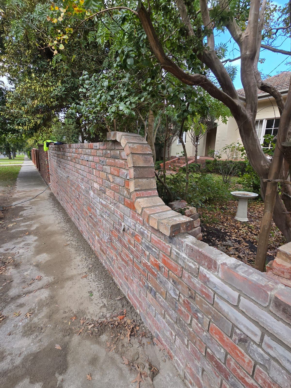 Restored heritage red-brick garden wall with a curved end and matched reclaimed brick by Goodwin Bricklaying
